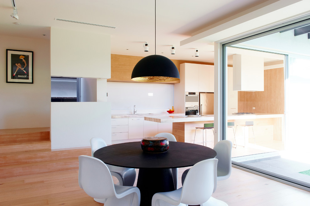 Photo of a large contemporary galley eat-in kitchen in Melbourne with a double-bowl sink, white cabinets, stainless steel appliances, light hardwood floors and with island.