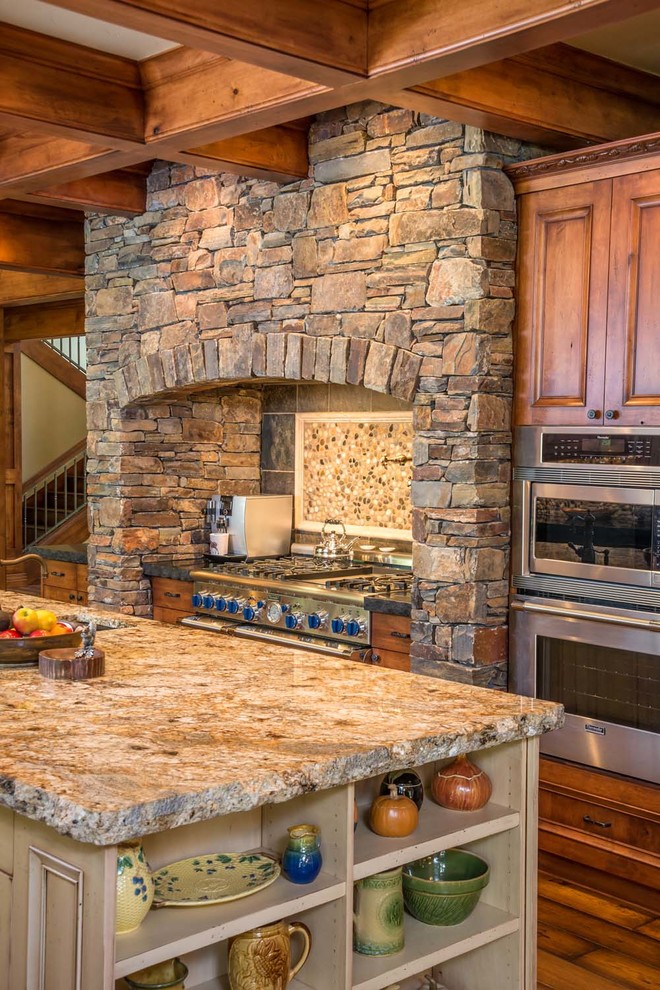 Inspiration for a large rustic u-shaped medium tone wood floor kitchen remodel with an undermount sink, beaded inset cabinets, medium tone wood cabinets, granite countertops, gray backsplash, stone tile backsplash, stainless steel appliances and an island