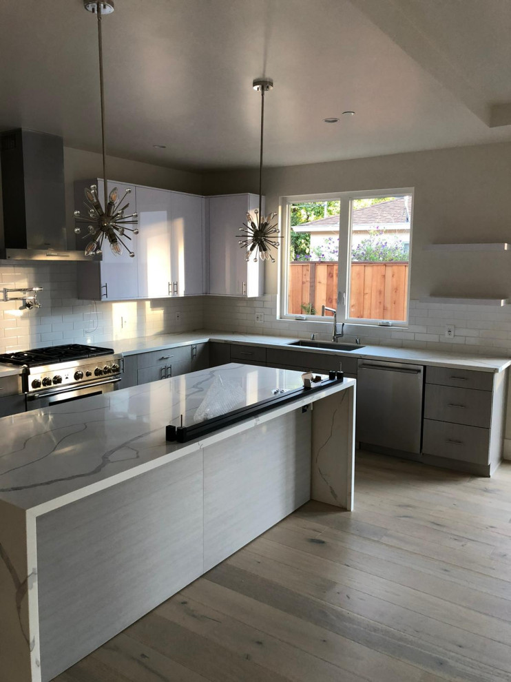 Exempel på ett mellanstort modernt vit vitt kök, med en undermonterad diskho, släta luckor, vita skåp, träbänkskiva, vitt stänkskydd, rostfria vitvaror, ljust trägolv, en köksö och grått golv