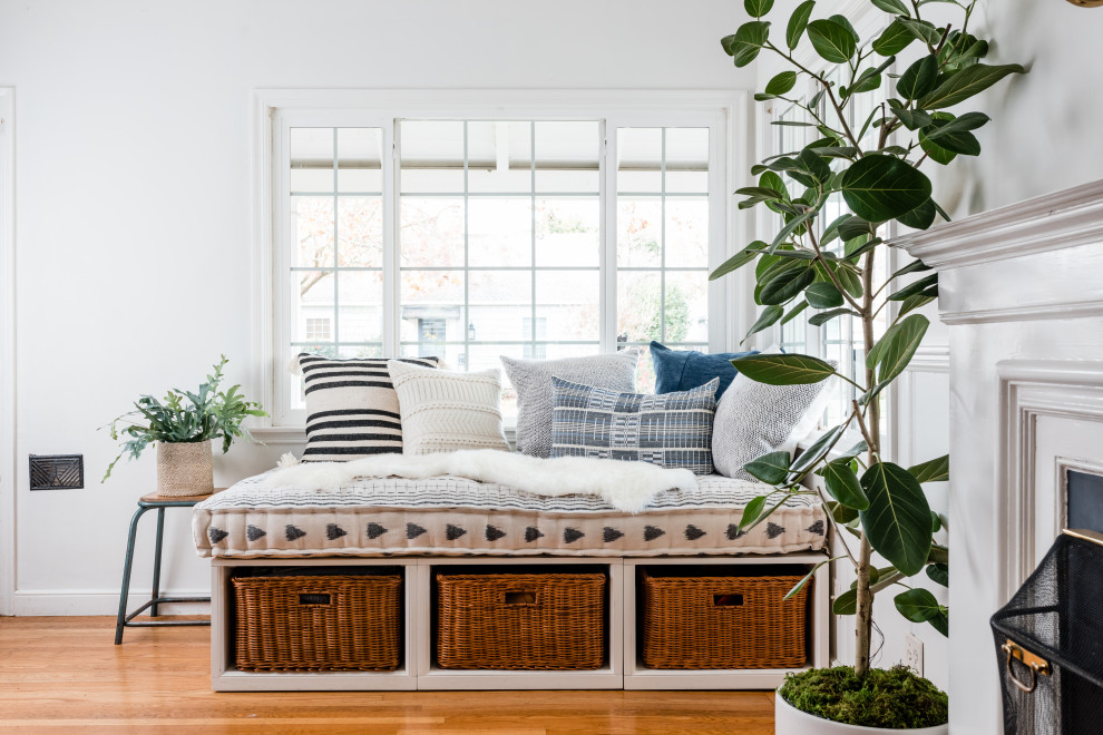 Inspiration for a mid-sized scandinavian living room in Sacramento with white walls, medium hardwood floors, a standard fireplace, a plaster fireplace surround and brown floor.