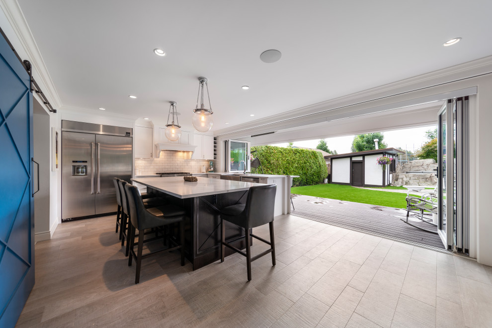 Transitional beige floor kitchen photo in Vancouver with white backsplash, stainless steel appliances, an island and white countertops
