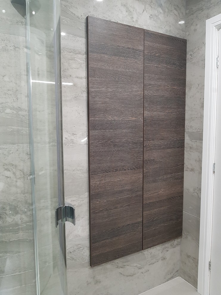 This is an example of a medium sized contemporary ensuite bathroom in Other with flat-panel cabinets, dark wood cabinets, a corner shower, a wall mounted toilet, grey tiles, porcelain tiles, grey walls, porcelain flooring, a wall-mounted sink, grey floors and a hinged door.