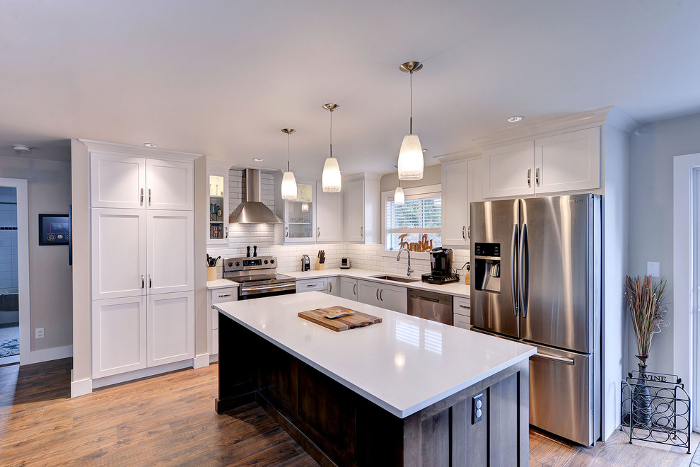 Inspiration for a transitional dark wood floor and brown floor enclosed kitchen remodel with a single-bowl sink, shaker cabinets, white cabinets, quartzite countertops, white backsplash, subway tile backsplash, stainless steel appliances and an island