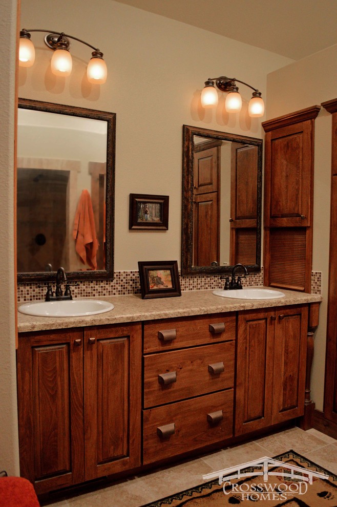 Mid-sized country master bathroom in Denver with a drop-in sink, raised-panel cabinets, medium wood cabinets, laminate benchtops, a double shower, a one-piece toilet, multi-coloured tile, glass tile, beige walls and porcelain floors.