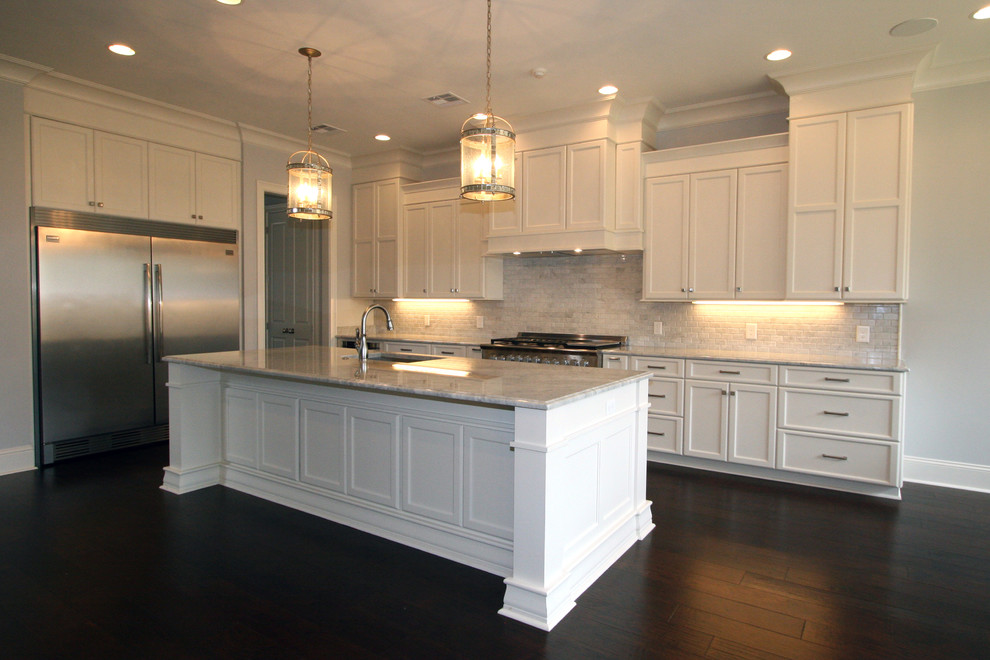 Photo of a mid-sized traditional single-wall eat-in kitchen in New Orleans with an undermount sink, shaker cabinets, white cabinets, marble benchtops, white splashback, stone tile splashback, stainless steel appliances, dark hardwood floors and with island.