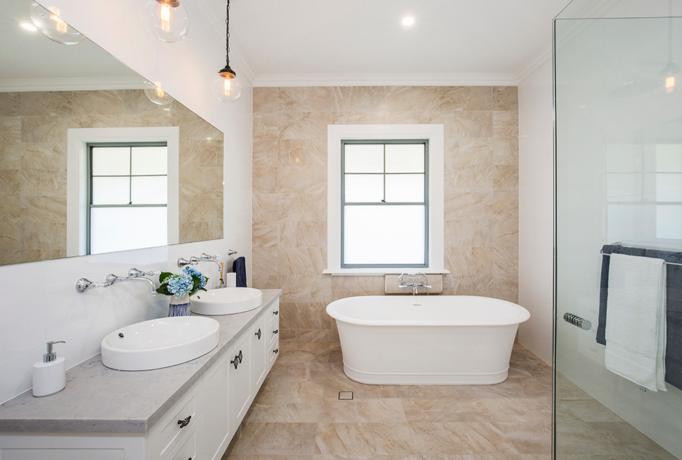 Inspiration for an expansive country 3/4 bathroom in Sydney with shaker cabinets, white cabinets, a freestanding tub, a corner shower, a one-piece toilet, white tile, ceramic tile, white walls, travertine floors, a drop-in sink, solid surface benchtops and a hinged shower door.