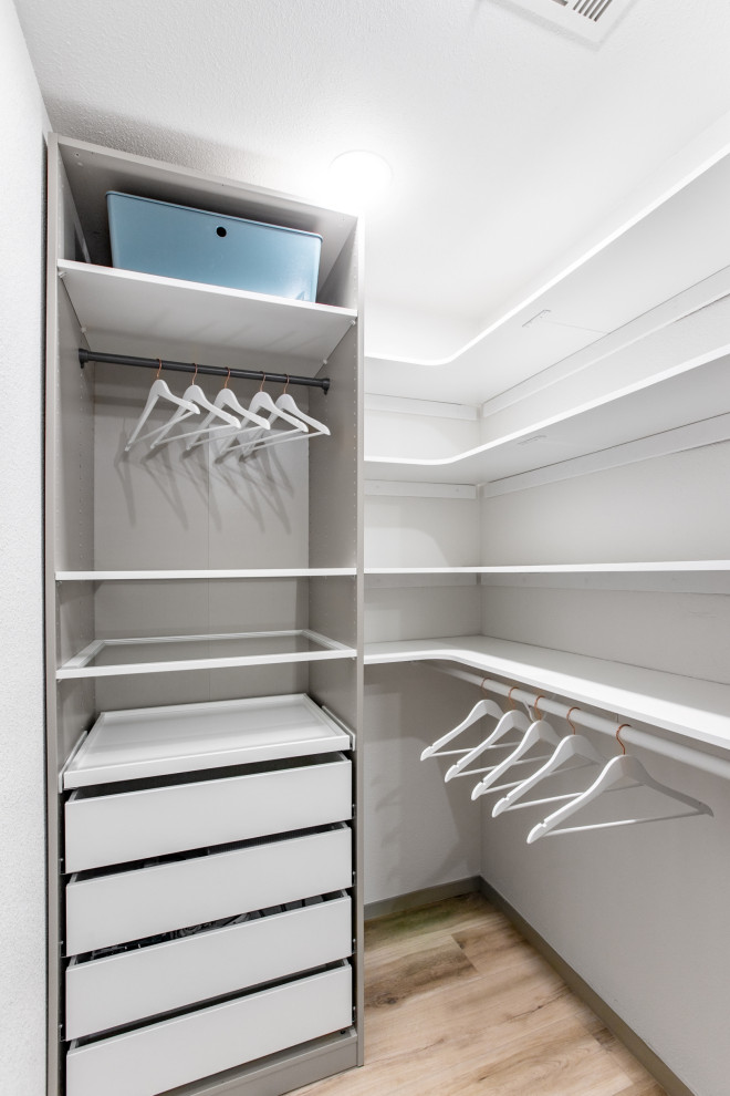 Photo of a large modern storage and wardrobe in Las Vegas with glass-front cabinets, white cabinets, vinyl floors and beige floor.