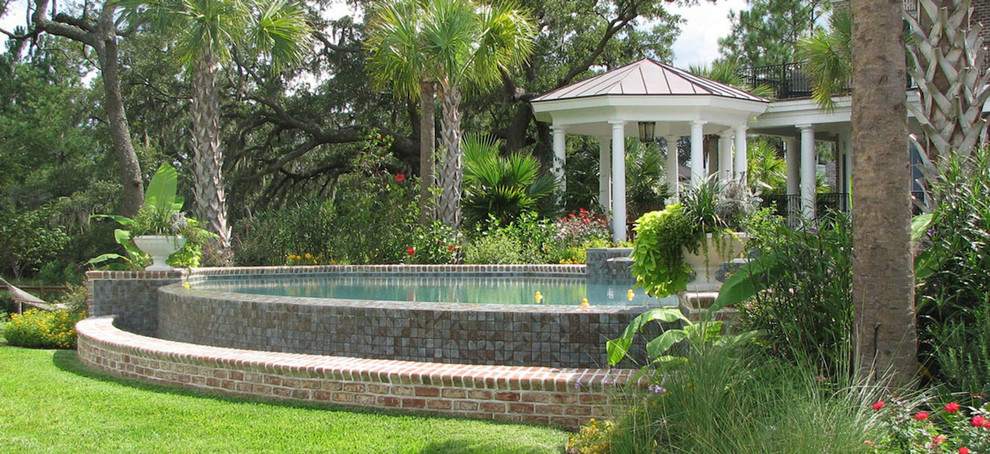 Large tropical backyard round aboveground pool in Charleston with natural stone pavers.