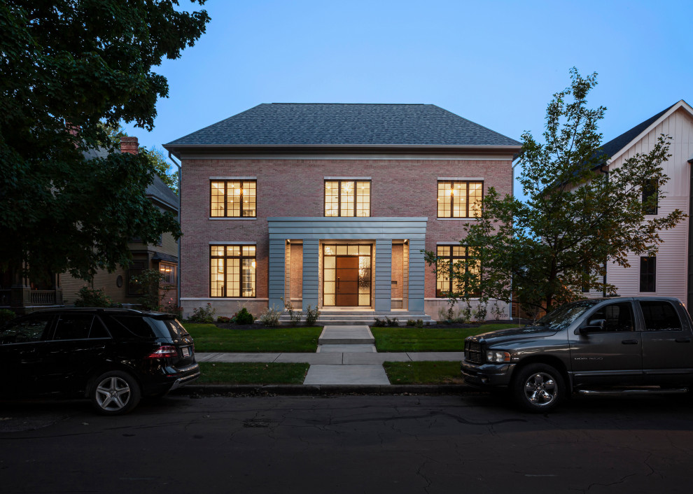 Mittelgroßes, Zweistöckiges Modernes Einfamilienhaus mit Backsteinfassade, pinker Fassadenfarbe, Walmdach, Schindeldach und grauem Dach in Indianapolis
