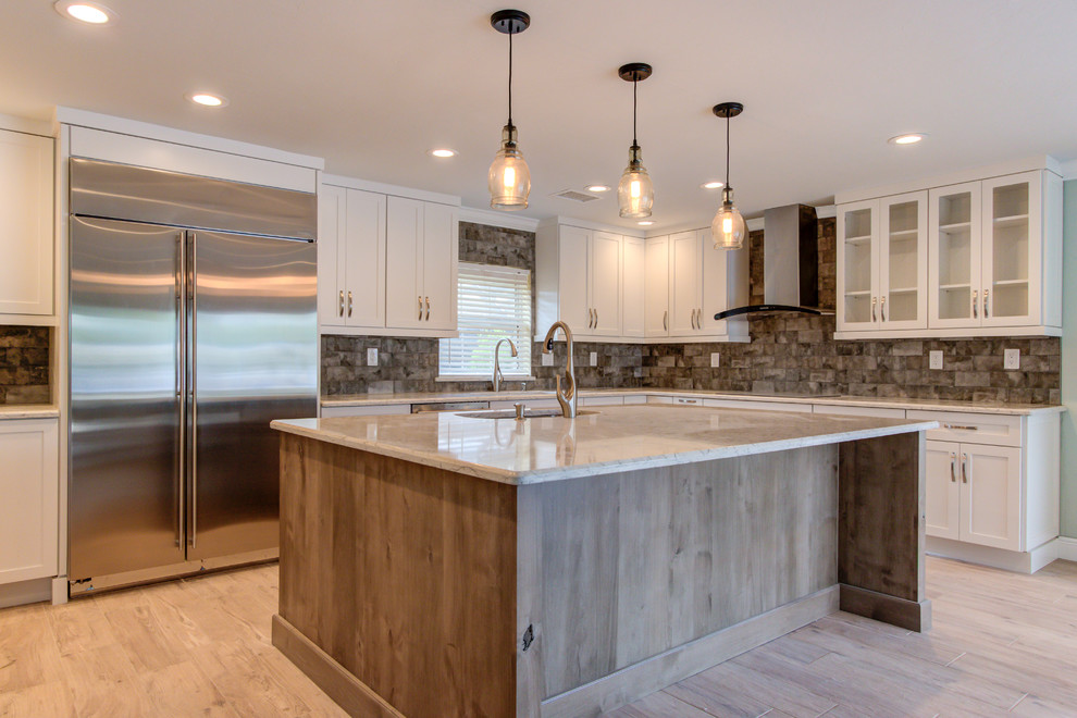 Large transitional u-shaped porcelain tile and brown floor enclosed kitchen photo with an undermount sink, shaker cabinets, white cabinets, quartz countertops, brown backsplash, stainless steel appliances, an island and beige countertops