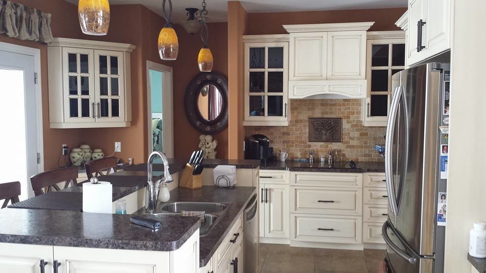 Photo of a mid-sized traditional l-shaped separate kitchen in Toronto with a double-bowl sink, raised-panel cabinets, white cabinets, limestone benchtops, beige splashback, travertine splashback, stainless steel appliances, travertine floors, with island and beige floor.