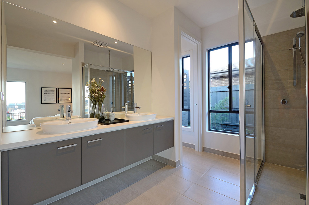 This is an example of a mid-sized contemporary 3/4 bathroom in Melbourne with a double shower, a one-piece toilet, gray tile, cement tile, white walls, ceramic floors, a drop-in sink and laminate benchtops.