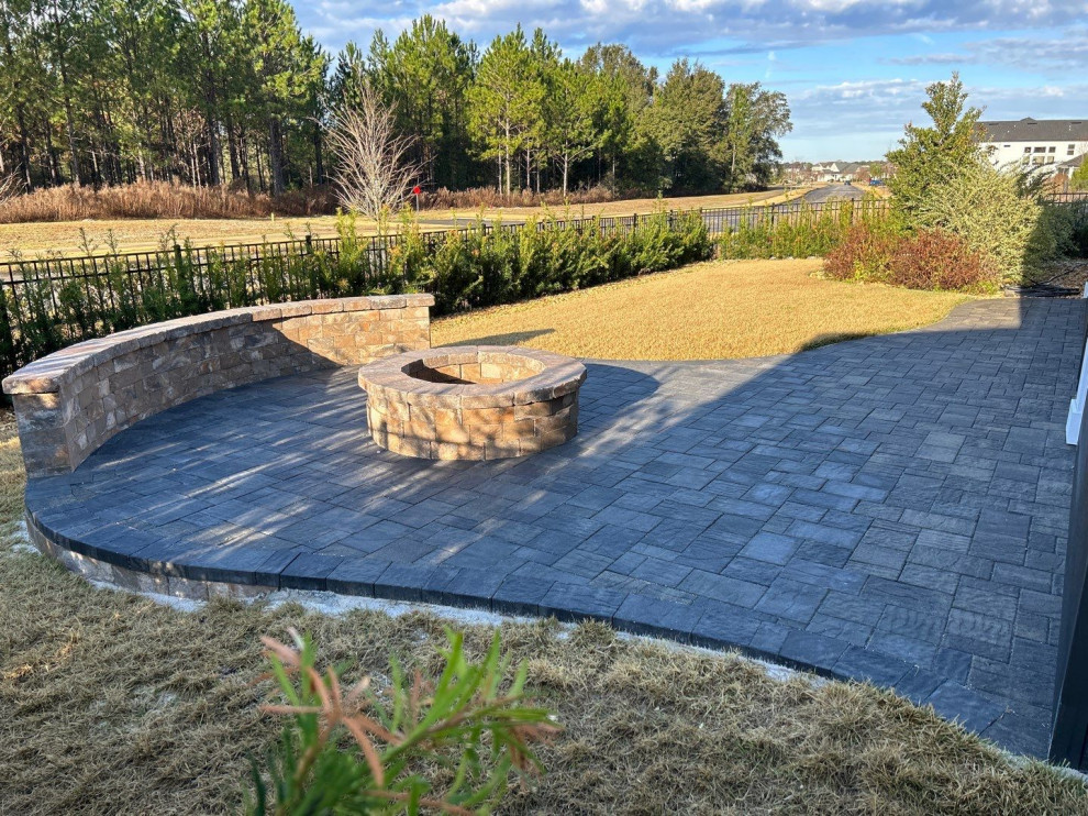 This is an example of a mid-sized traditional backyard full sun garden for winter in Jacksonville with a fire feature, brick pavers and a metal fence.