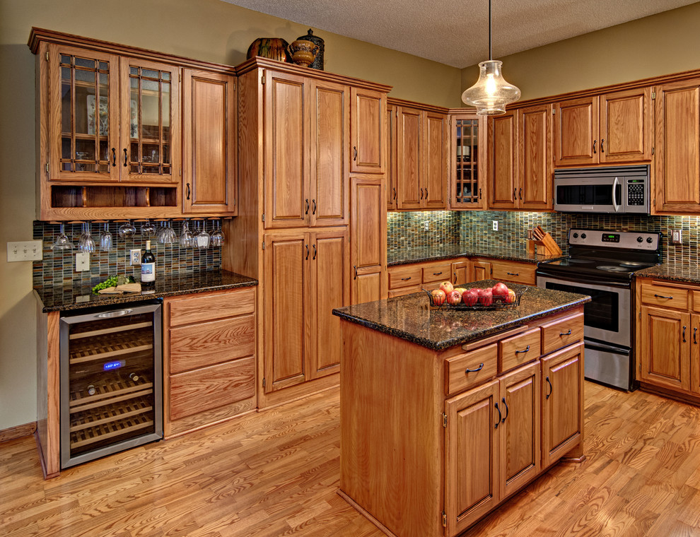 Photo of a large traditional u-shaped eat-in kitchen in Minneapolis with an undermount sink, raised-panel cabinets, light wood cabinets, quartz benchtops, multi-coloured splashback, mosaic tile splashback, stainless steel appliances, light hardwood floors, with island and beige floor.