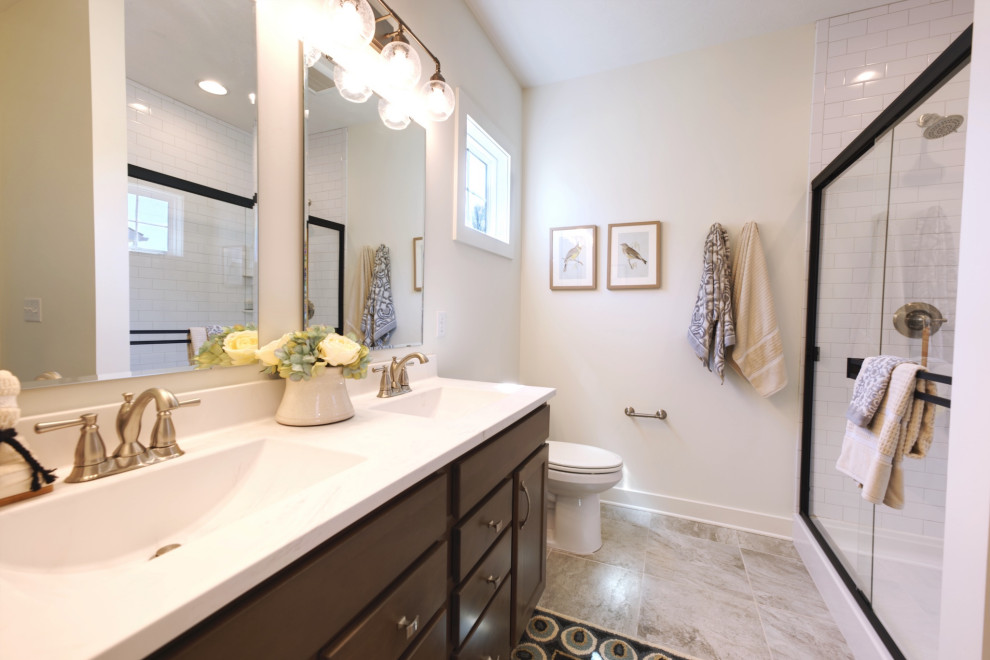 Exempel på ett mellanstort lantligt vit vitt en-suite badrum, med luckor med infälld panel, skåp i mellenmörkt trä, en dusch i en alkov, en toalettstol med hel cisternkåpa, vit kakel, tunnelbanekakel, vita väggar, klinkergolv i keramik, ett integrerad handfat, marmorbänkskiva, flerfärgat golv och dusch med skjutdörr