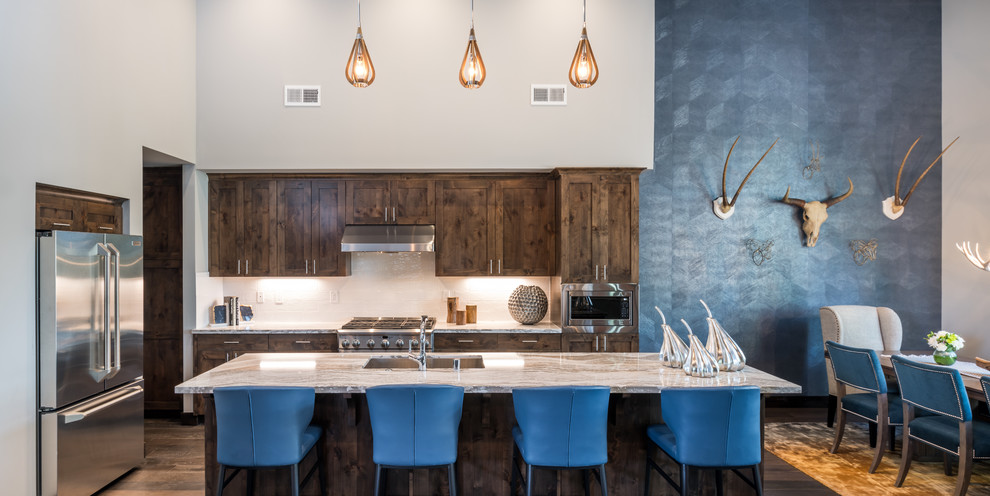 Example of a transitional dark wood floor and brown floor open concept kitchen design with an undermount sink, shaker cabinets, dark wood cabinets, white backsplash, stainless steel appliances, an island, quartz countertops and white countertops