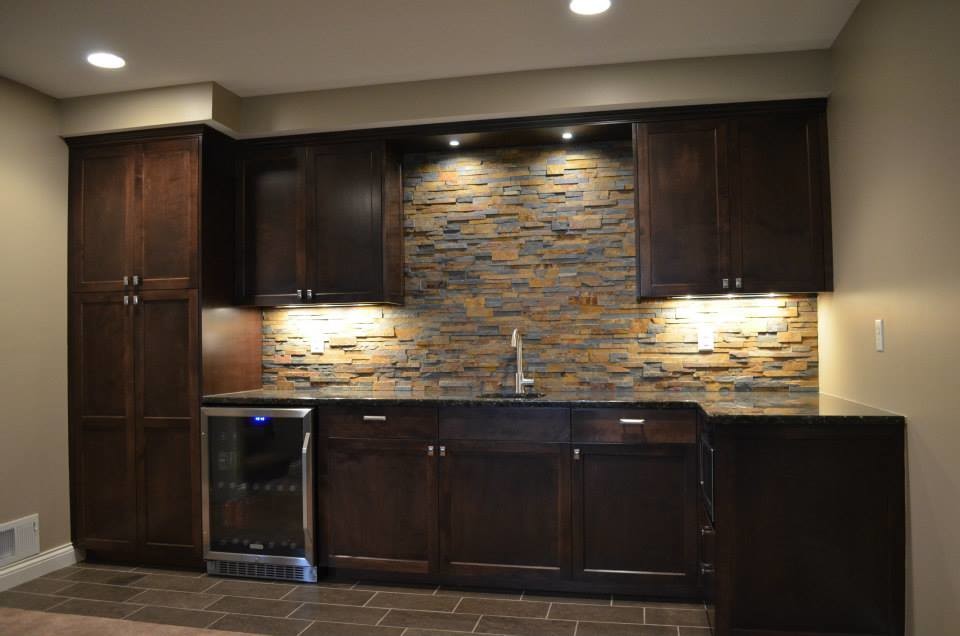 This is an example of a modern single-wall home bar in Minneapolis with an undermount sink, shaker cabinets, dark wood cabinets, granite benchtops, multi-coloured splashback, stone slab splashback and ceramic floors.