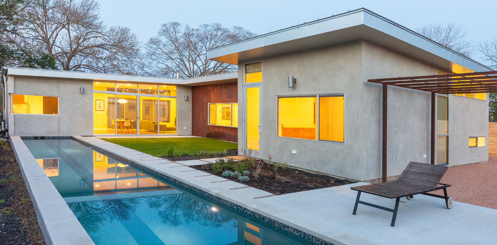 Photo of a midcentury rectangular lap pool in Austin with concrete slab.