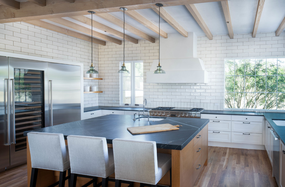 Example of a large transitional u-shaped medium tone wood floor and brown floor open concept kitchen design in Phoenix with shaker cabinets, white cabinets, soapstone countertops, white backsplash, ceramic backsplash, stainless steel appliances and an island