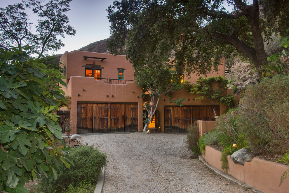 Expansive mediterranean two-storey adobe red house exterior in Los Angeles with a flat roof.