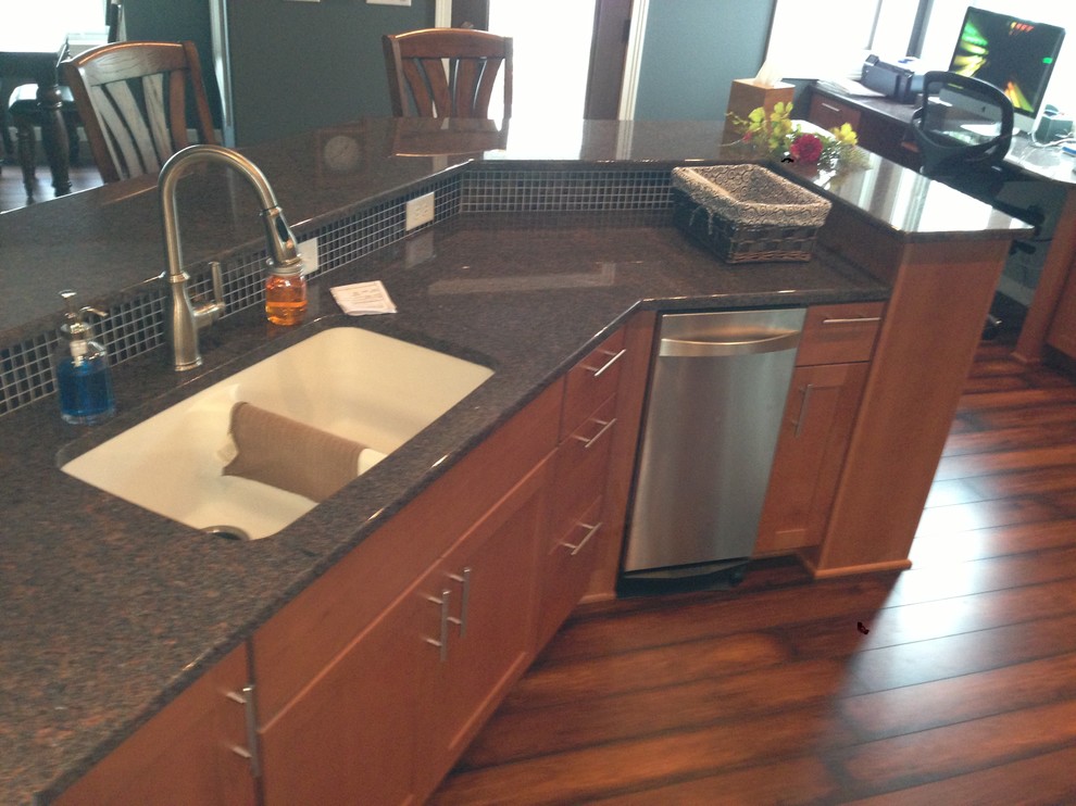 Inspiration for a transitional u-shaped medium tone wood floor open concept kitchen remodel with an undermount sink, flat-panel cabinets, medium tone wood cabinets, granite countertops, black backsplash, glass tile backsplash, stainless steel appliances and a peninsula