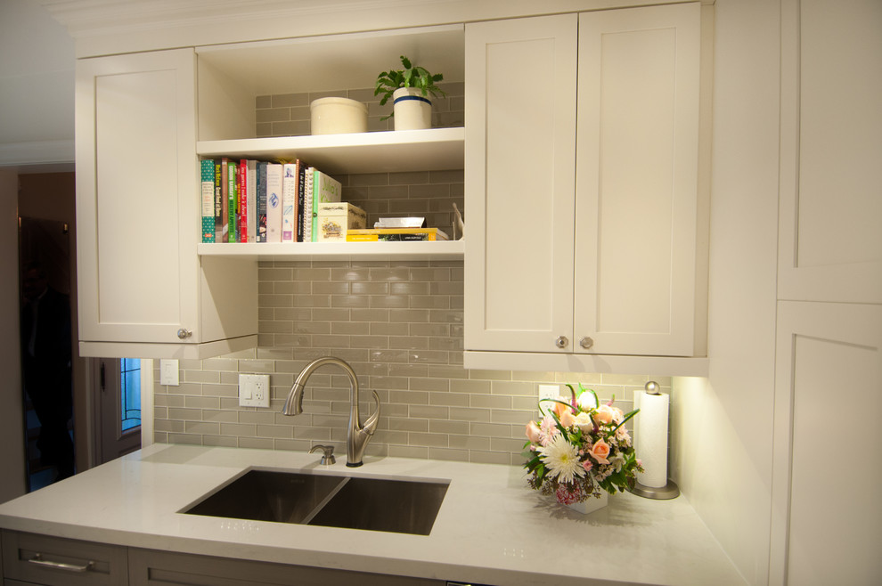 Enclosed kitchen - mid-sized transitional galley ceramic tile enclosed kitchen idea in Toronto with a double-bowl sink, shaker cabinets, white cabinets, quartzite countertops, gray backsplash, glass tile backsplash, stainless steel appliances and no island