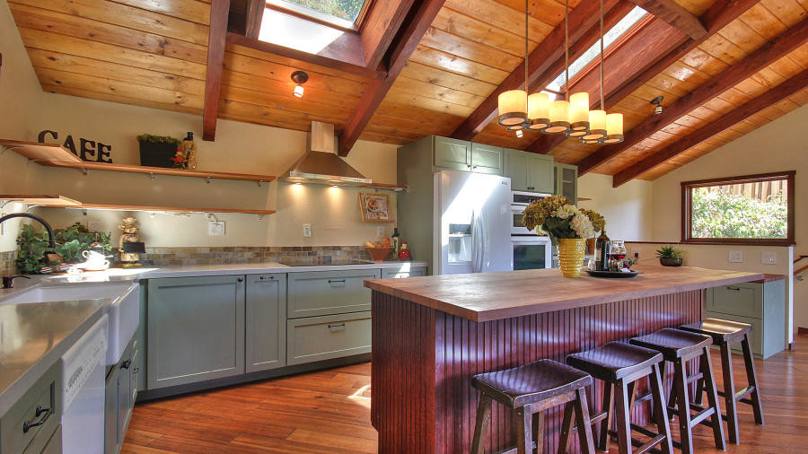 Photo of a large country l-shaped eat-in kitchen in San Francisco with stainless steel appliances, medium hardwood floors, with island, a farmhouse sink, raised-panel cabinets, green cabinets, granite benchtops and brown floor.