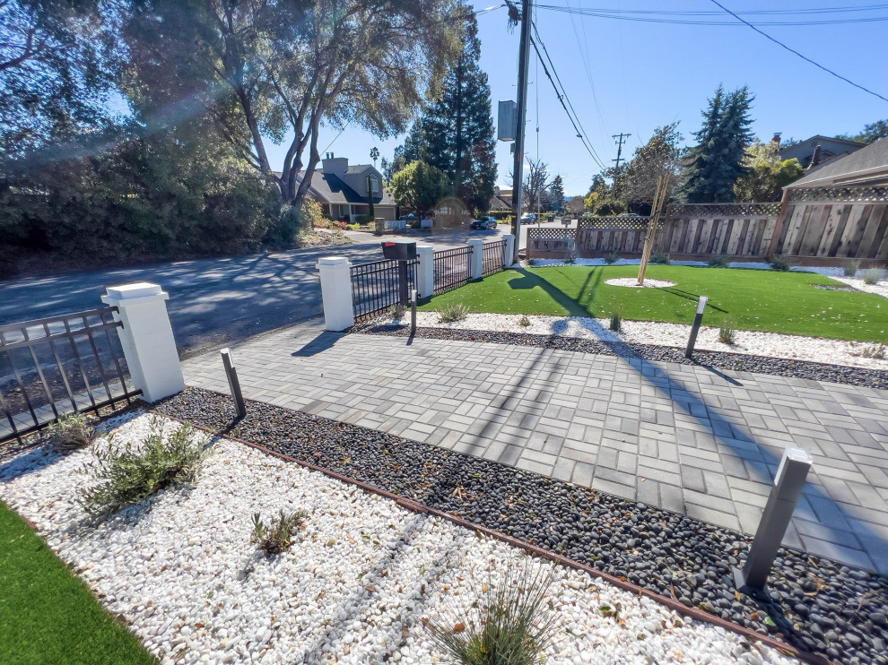 Immagine di un vialetto minimalista davanti casa con pavimentazioni in cemento e recinzione in metallo