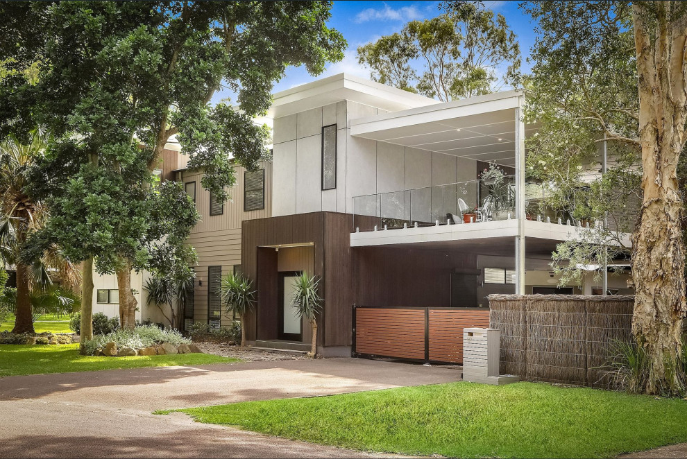 This is an example of a mid-sized contemporary two-storey grey house exterior in Central Coast with concrete fiberboard siding, a flat roof and a metal roof.