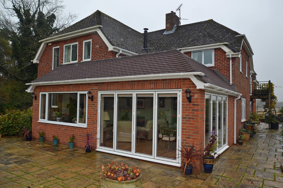 Photo of a contemporary one-storey brick red exterior in Berkshire with a clipped gable roof.