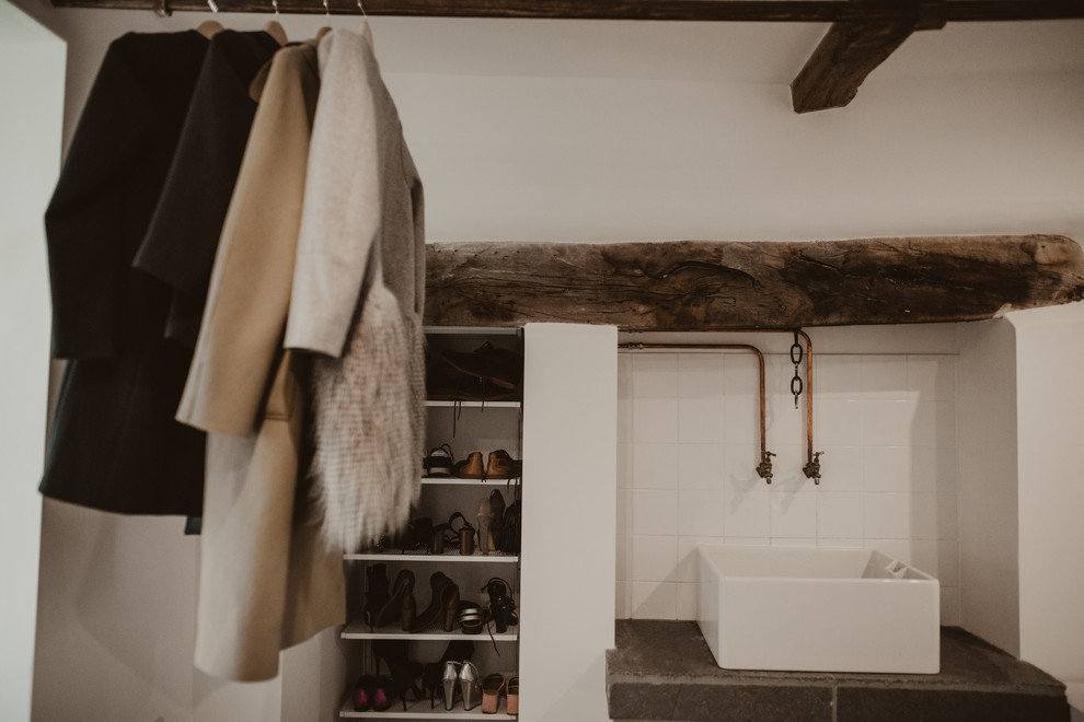Photo of a mid-sized eclectic laundry room in Other with a farmhouse sink, quartz benchtops, white splashback, ceramic splashback, white walls, limestone floors, grey floor, grey benchtop and exposed beam.
