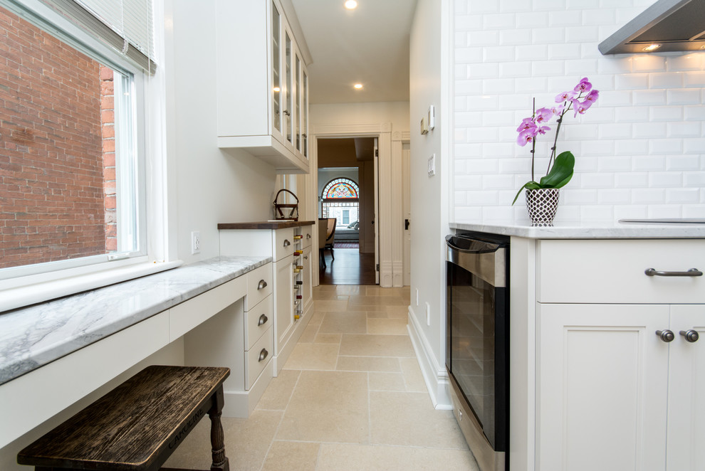 Inspiration for a mid-sized transitional l-shaped cement tile floor eat-in kitchen remodel in Toronto with an undermount sink, shaker cabinets, white cabinets, marble countertops, white backsplash, subway tile backsplash, stainless steel appliances and an island
