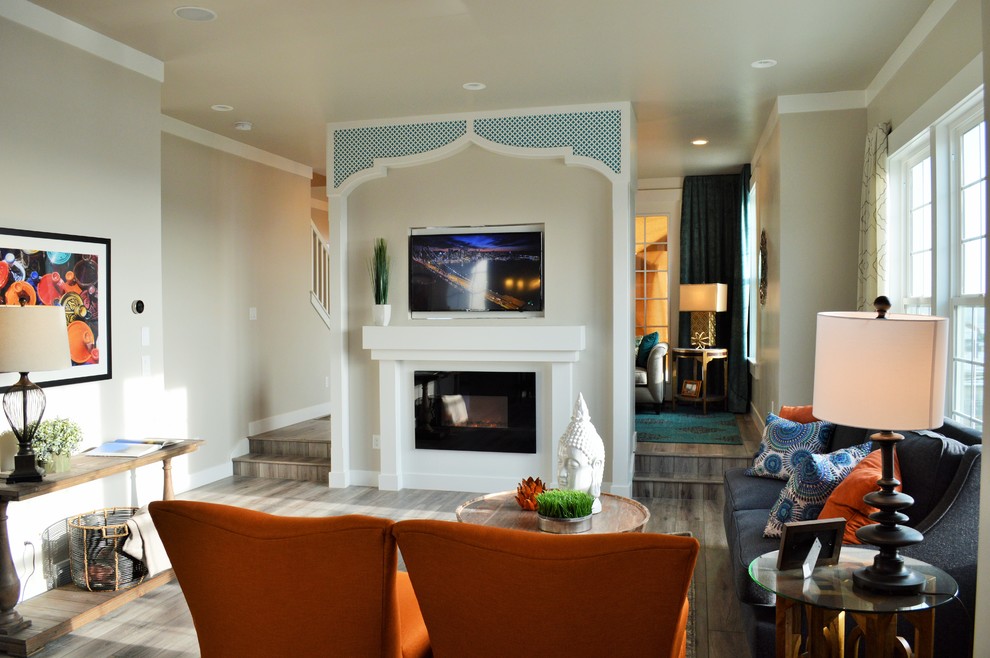 This is an example of a mid-sized mediterranean open concept living room in Salt Lake City with grey walls, light hardwood floors, a standard fireplace, a plaster fireplace surround and a wall-mounted tv.