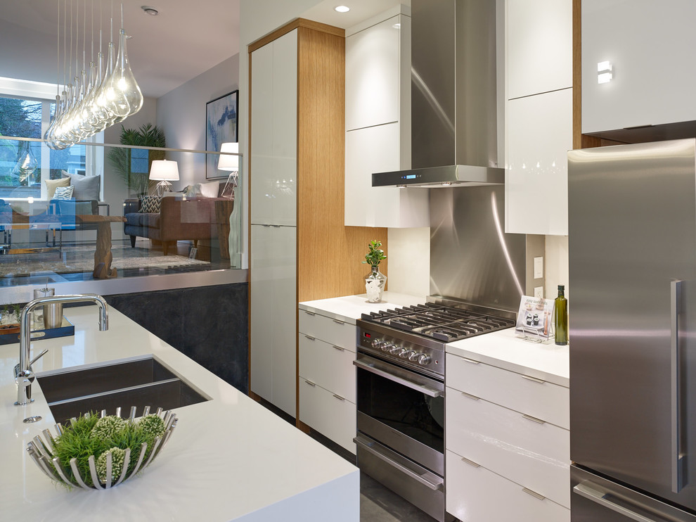 Photo of a mid-sized contemporary galley eat-in kitchen in Vancouver with an undermount sink, flat-panel cabinets, white cabinets, quartz benchtops, white splashback, glass sheet splashback, stainless steel appliances, concrete floors and with island.