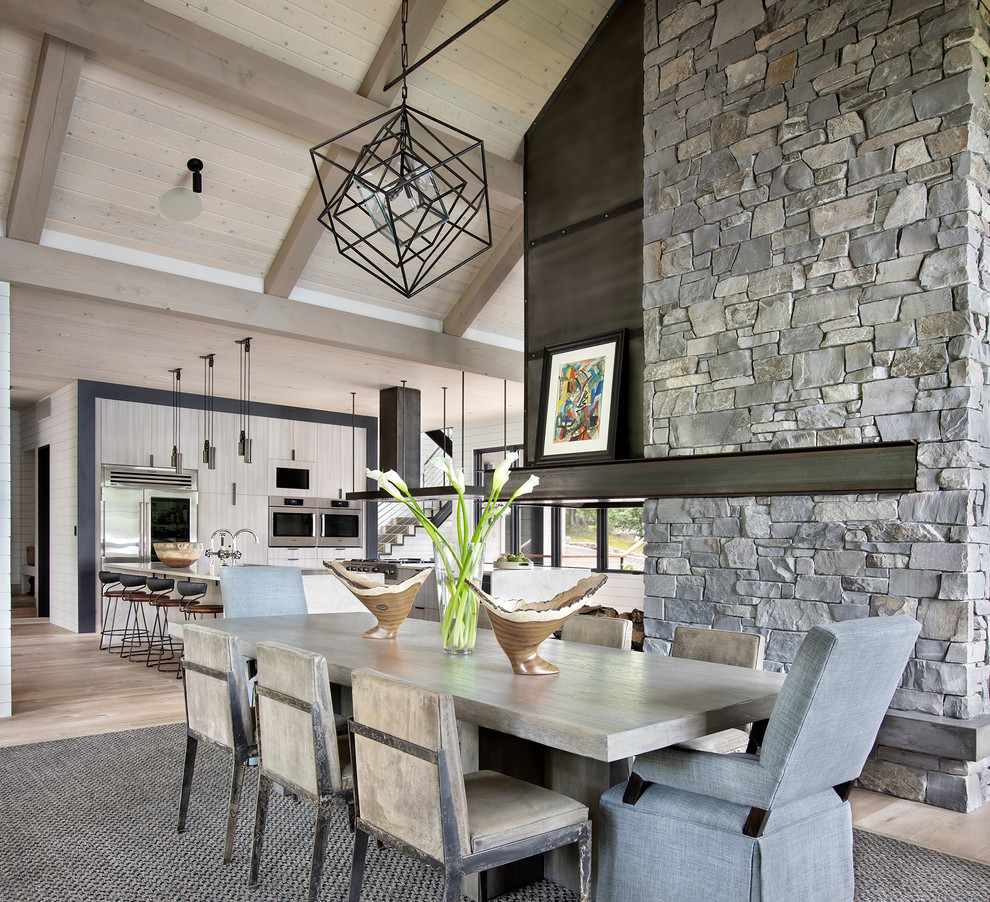 Country kitchen/dining combo in Other with light hardwood floors, a two-sided fireplace and beige floor.