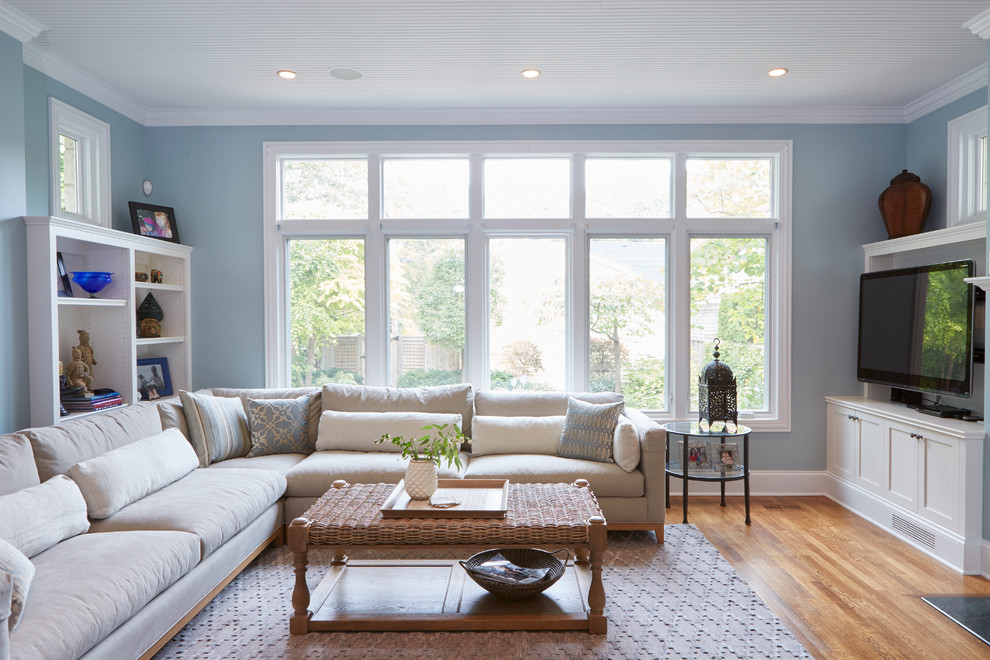 Photo of a beach style living room in Chicago with blue walls, light hardwood floors and a wall-mounted tv.