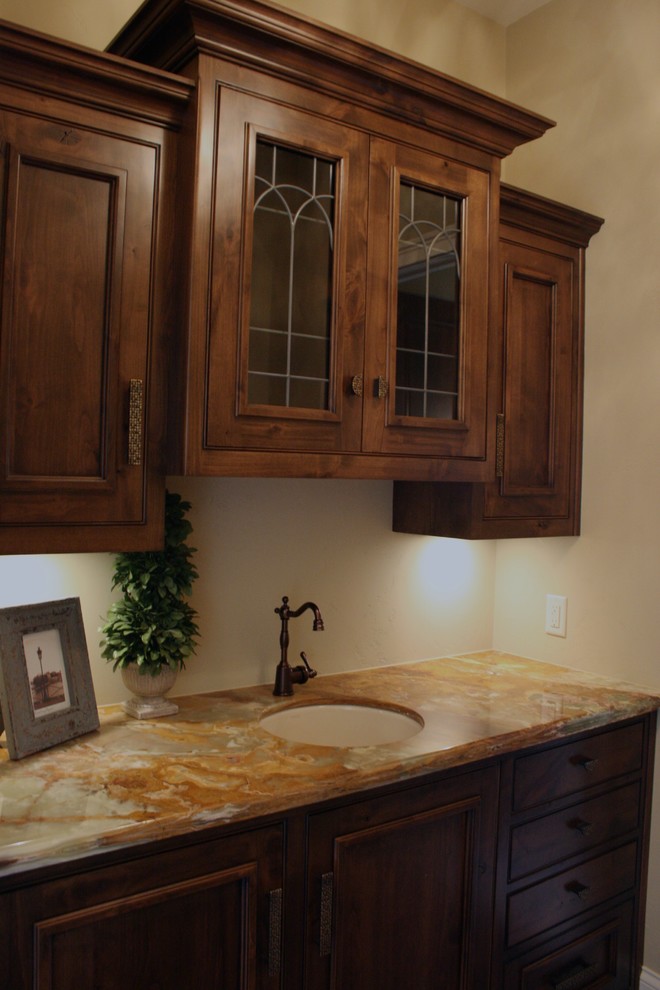 Photo of a mid-sized mediterranean single-wall wet bar in Other with an undermount sink, dark wood cabinets, dark hardwood floors, beaded inset cabinets and onyx benchtops.