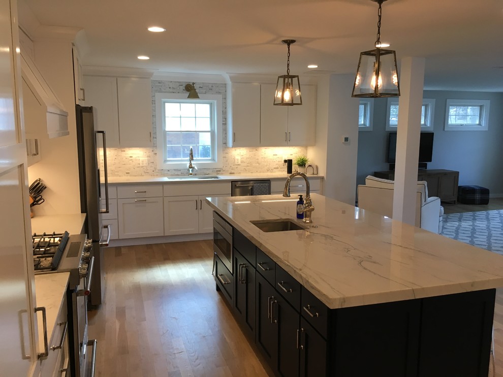 Mid-sized transitional u-shaped brown floor open concept kitchen photo in DC Metro with an undermount sink, shaker cabinets, white cabinets, gray backsplash, stainless steel appliances, an island and white countertops