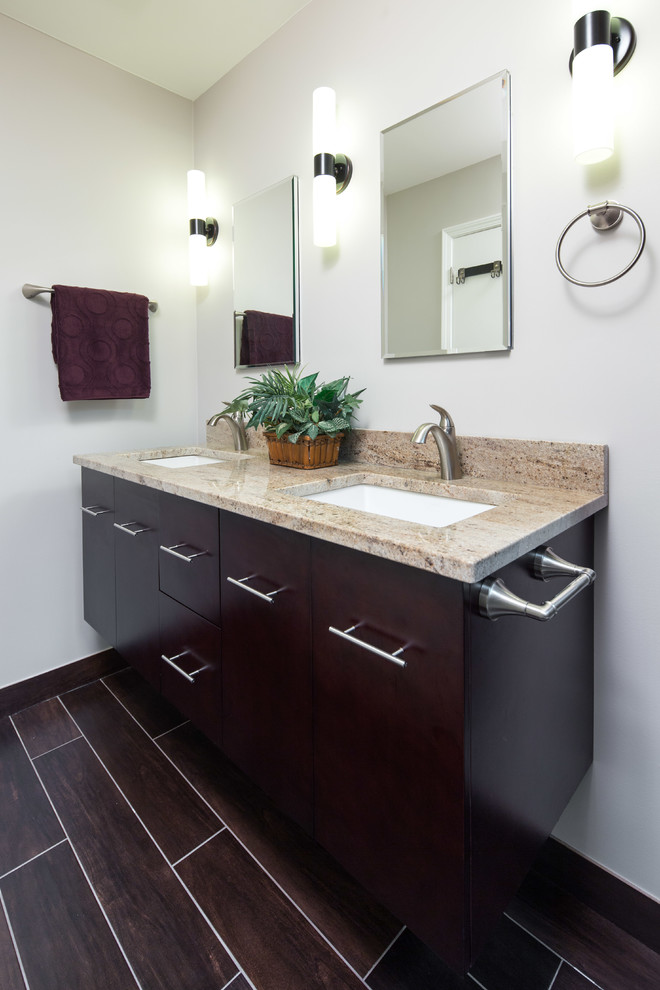 This is an example of a mid-sized transitional master bathroom in Chicago with an undermount sink, flat-panel cabinets, dark wood cabinets, granite benchtops, an alcove shower, a two-piece toilet, multi-coloured tile, stone tile, grey walls and porcelain floors.