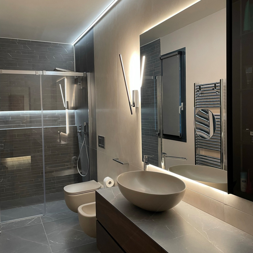 This is an example of a mid-sized modern master bathroom in Milan with glass-front cabinets, light wood cabinets, a hot tub, a curbless shower, a wall-mount toilet, beige tile, porcelain tile, beige walls, porcelain floors, an integrated sink, marble benchtops, beige floor, a sliding shower screen, beige benchtops, a single vanity, a floating vanity, recessed and decorative wall panelling.