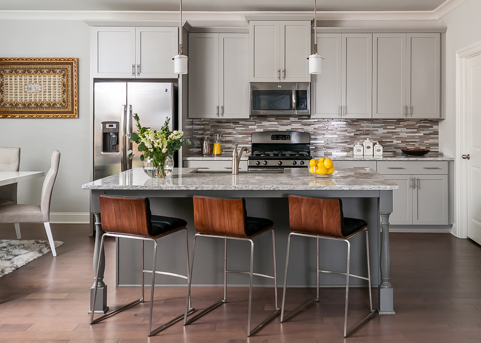 Photo of a mid-sized transitional single-wall eat-in kitchen in Atlanta with grey cabinets, multi-coloured splashback, matchstick tile splashback, stainless steel appliances, with island, a drop-in sink, granite benchtops, shaker cabinets and medium hardwood floors.