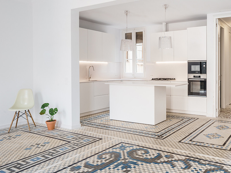 This is an example of a mid-sized transitional l-shaped open plan kitchen in Barcelona with a single-bowl sink, flat-panel cabinets, white cabinets, quartz benchtops, white splashback, engineered quartz splashback, stainless steel appliances, ceramic floors, with island, multi-coloured floor and white benchtop.