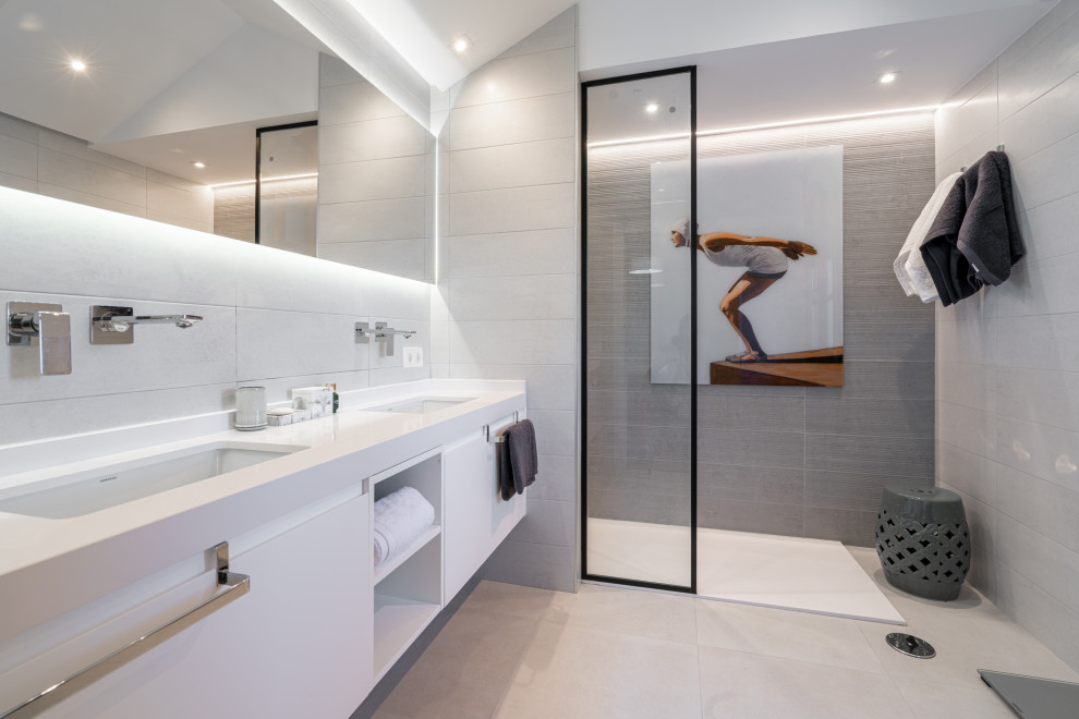 This is an example of a large contemporary 3/4 wet room bathroom in Other with flat-panel cabinets, white cabinets, a two-piece toilet, gray tile, ceramic tile, grey walls, porcelain floors, an undermount sink, engineered quartz benchtops, grey floor, an open shower, white benchtops, an enclosed toilet, a double vanity and a built-in vanity.