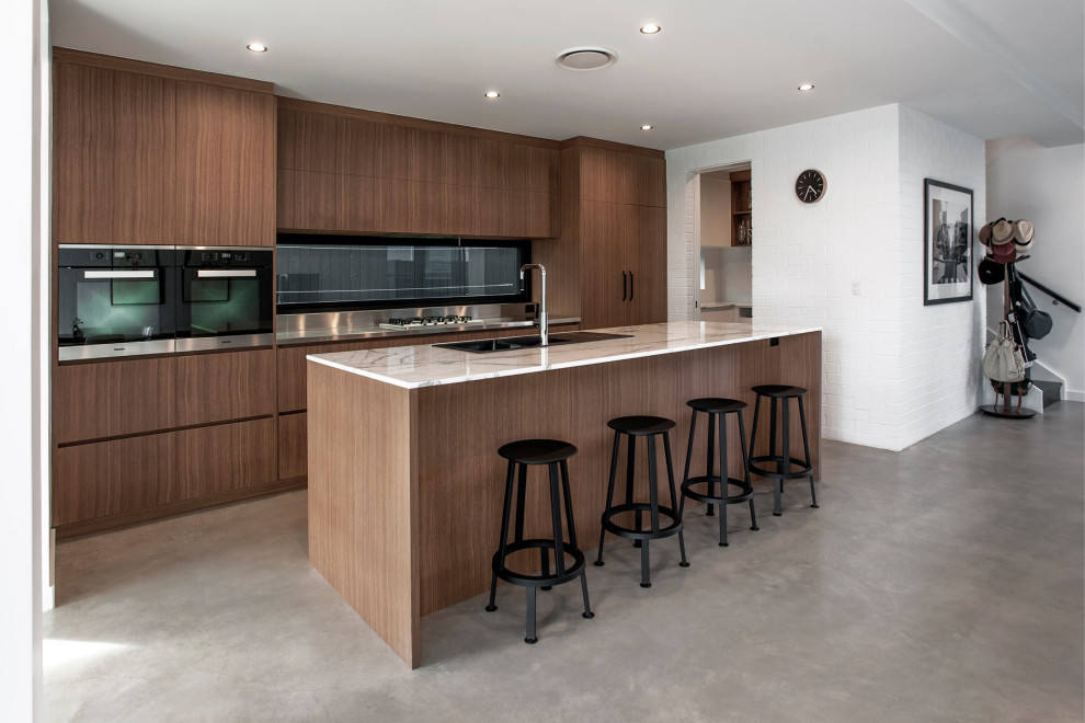 Design ideas for a contemporary galley open plan kitchen with a double-bowl sink, medium wood cabinets, marble benchtops, concrete floors, with island, white benchtop and window splashback.