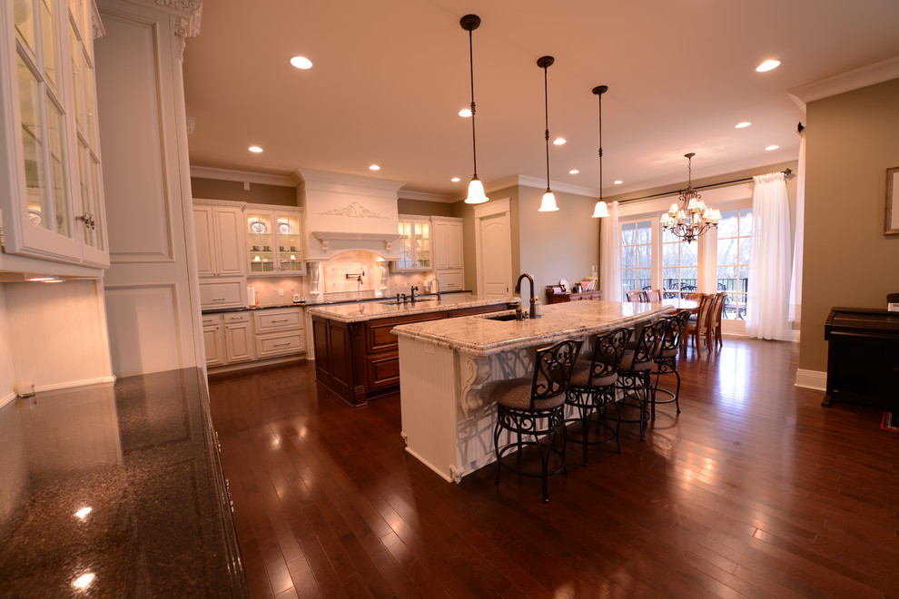 Design ideas for an expansive traditional kitchen in Indianapolis with raised-panel cabinets, white cabinets, granite benchtops, stone tile splashback and multiple islands.