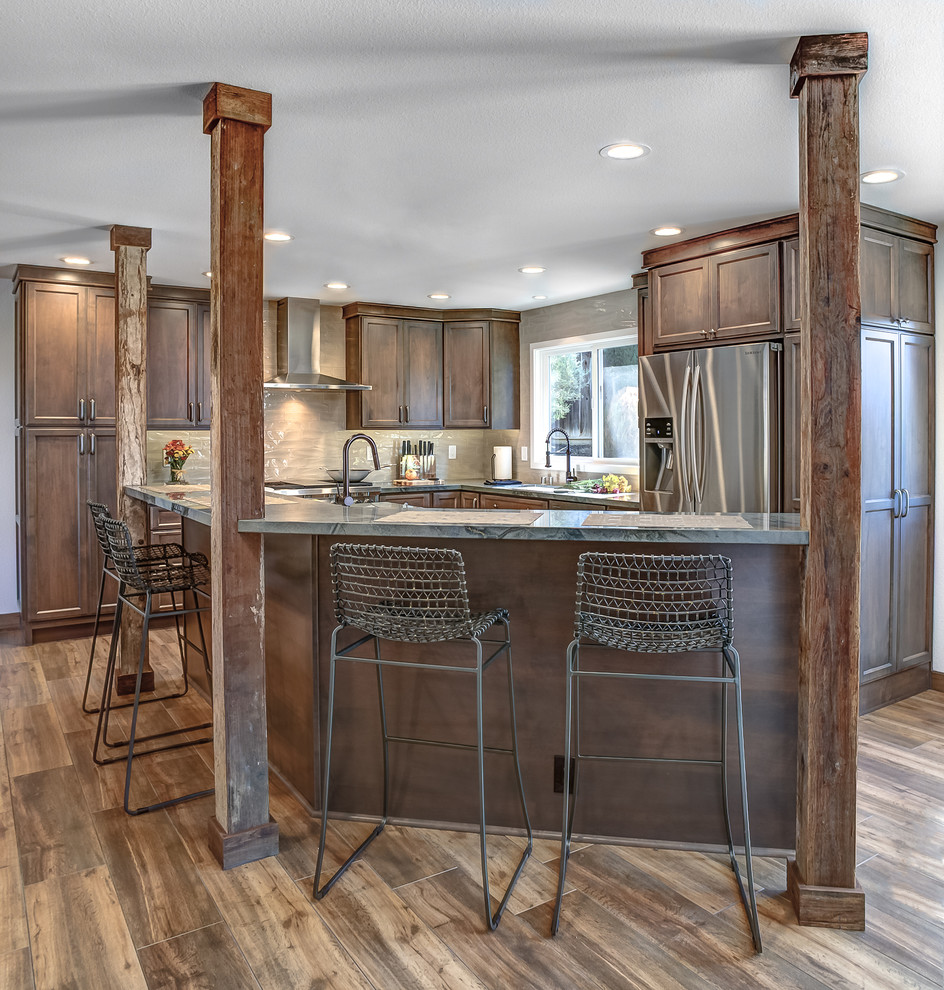 Photo of a large country l-shaped open plan kitchen in San Francisco with a single-bowl sink, raised-panel cabinets, brown cabinets, granite benchtops, beige splashback, ceramic splashback, stainless steel appliances, porcelain floors and with island.