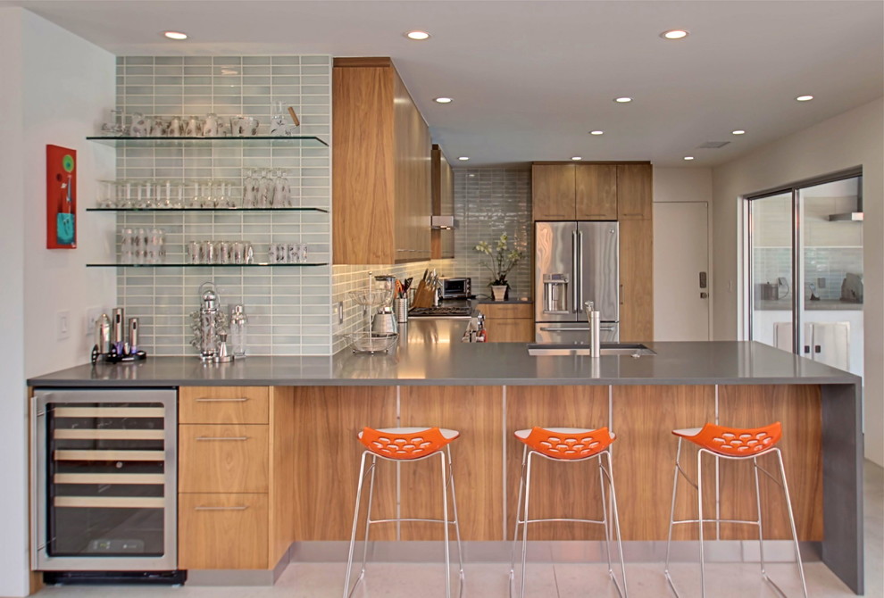 Inspiration for a midcentury l-shaped eat-in kitchen in Los Angeles with flat-panel cabinets, medium wood cabinets, grey splashback, subway tile splashback, stainless steel appliances, concrete floors and a peninsula.