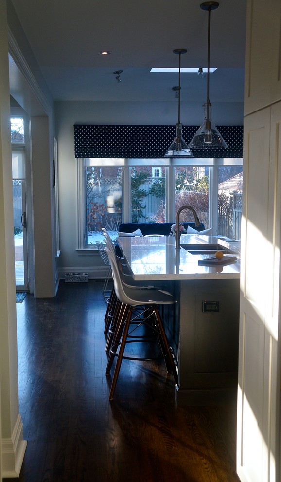 Transitional galley dark wood floor kitchen photo in Toronto with an undermount sink, shaker cabinets, white cabinets, quartz countertops, blue backsplash, glass tile backsplash, stainless steel appliances and an island