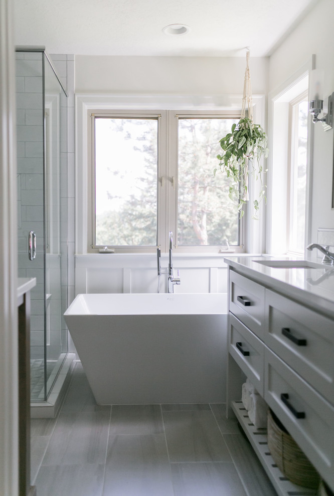 This is an example of a small arts and crafts master bathroom in Portland with open cabinets, grey cabinets, a freestanding tub, a corner shower, a one-piece toilet, white tile, subway tile, white walls, ceramic floors, a drop-in sink, engineered quartz benchtops, grey floor, a hinged shower door and white benchtops.
