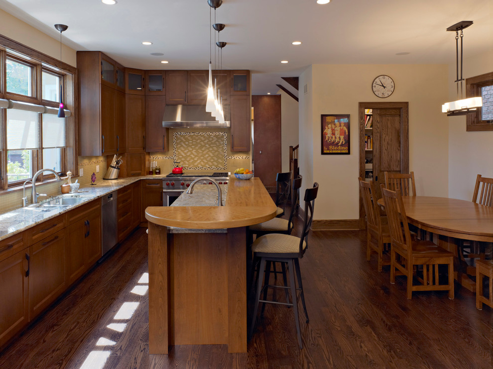 This is an example of a large traditional l-shaped eat-in kitchen in Chicago with a double-bowl sink, recessed-panel cabinets, medium wood cabinets, wood benchtops, beige splashback, mosaic tile splashback, stainless steel appliances and dark hardwood floors.